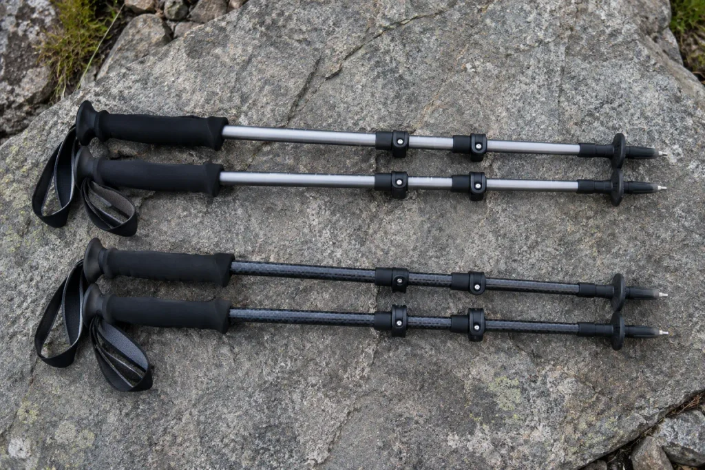 Trekking Poles for Women: Do You Actually Need Them? (And How to Use Them) Aluminium and carbon trekking poles laid side by side on a stone surface